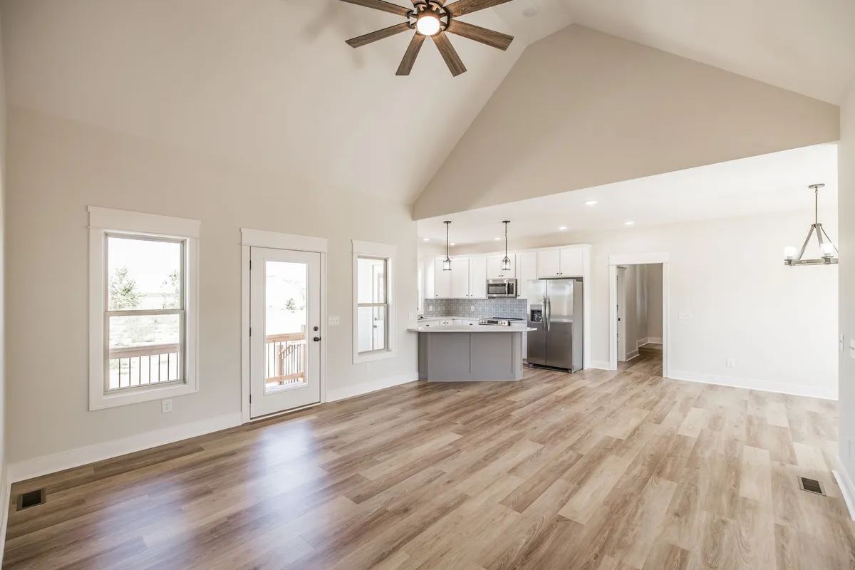Open great room with vaulted ceiling flowing into the kitchen and laminate wood floors at 1204 Vickie Ln