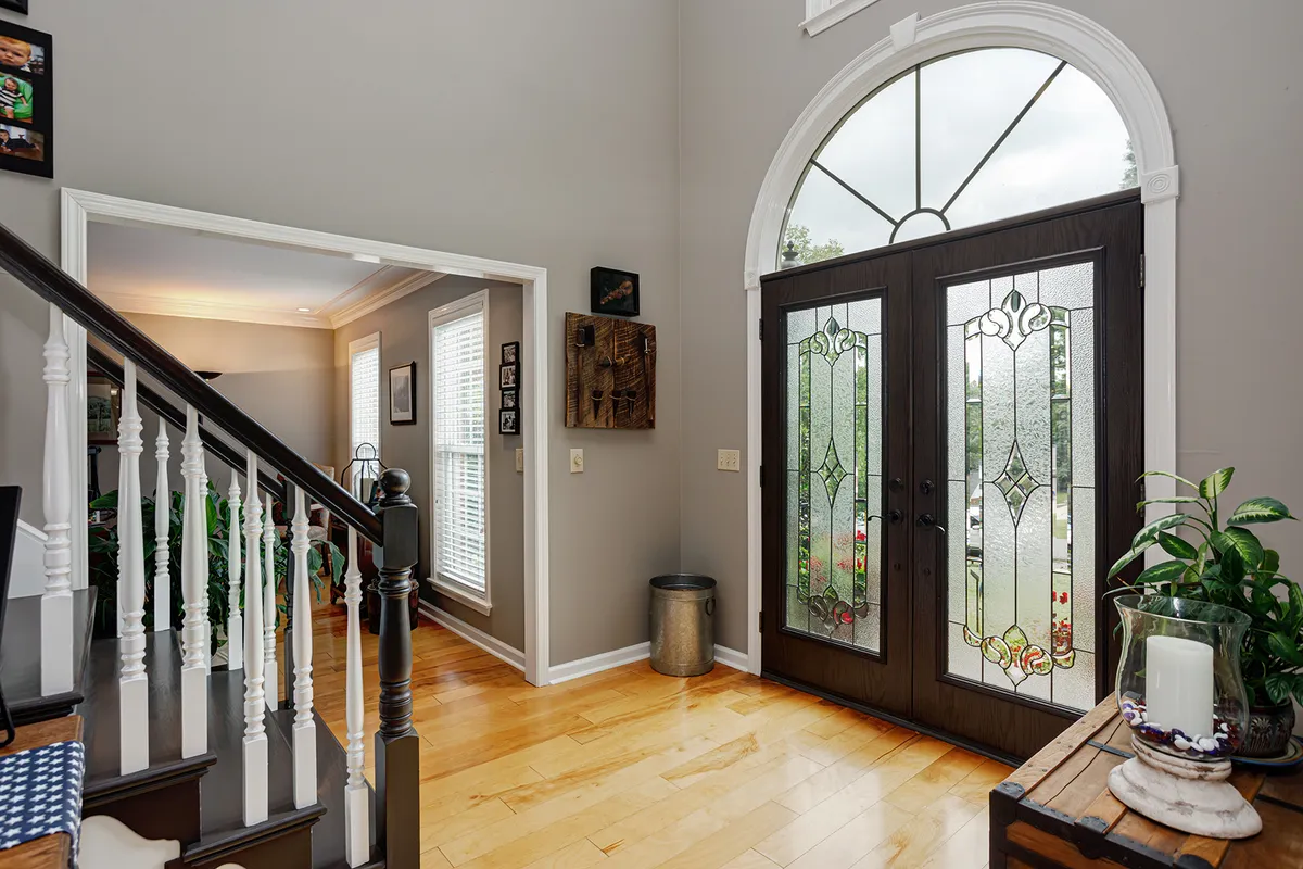 Two-story entry foyer with grand double doors, an arched window, and hardwood floors at 129 Baldridge Dr