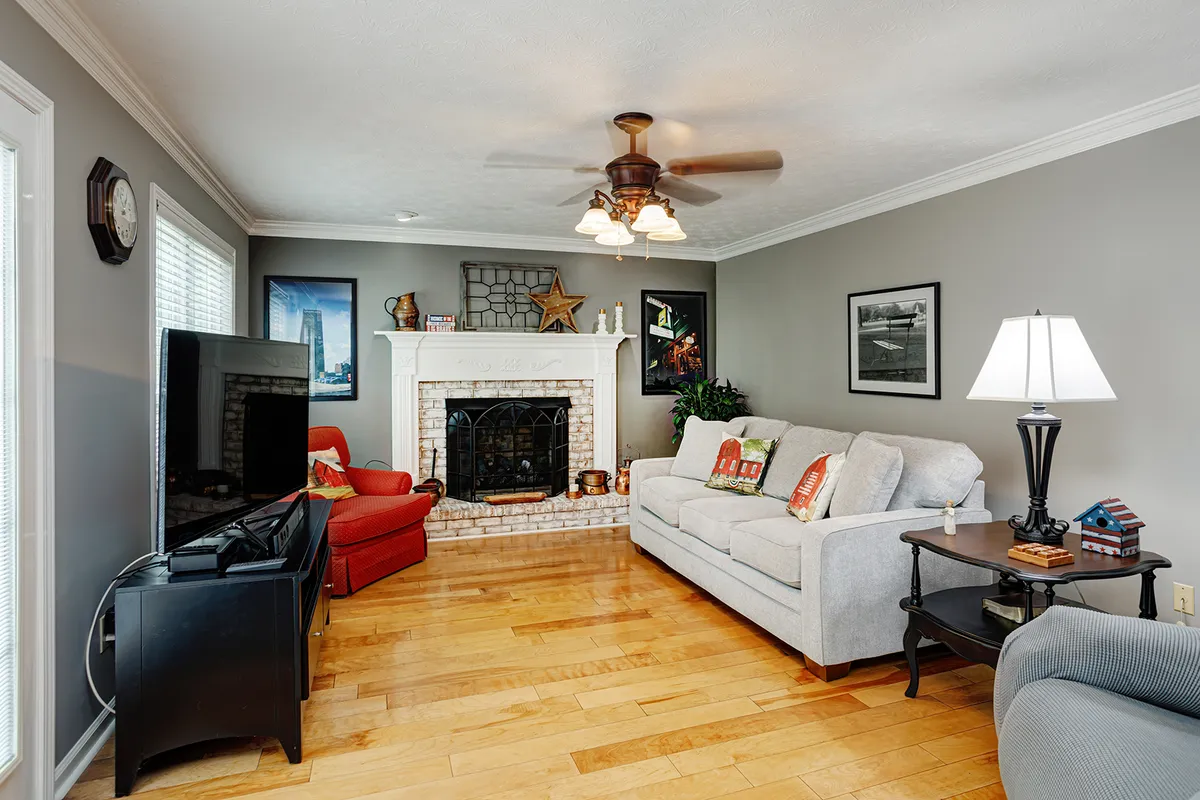 Living room with a fireplace, hardwood floors, and a ceiling fan at 129 Baldridge Dr