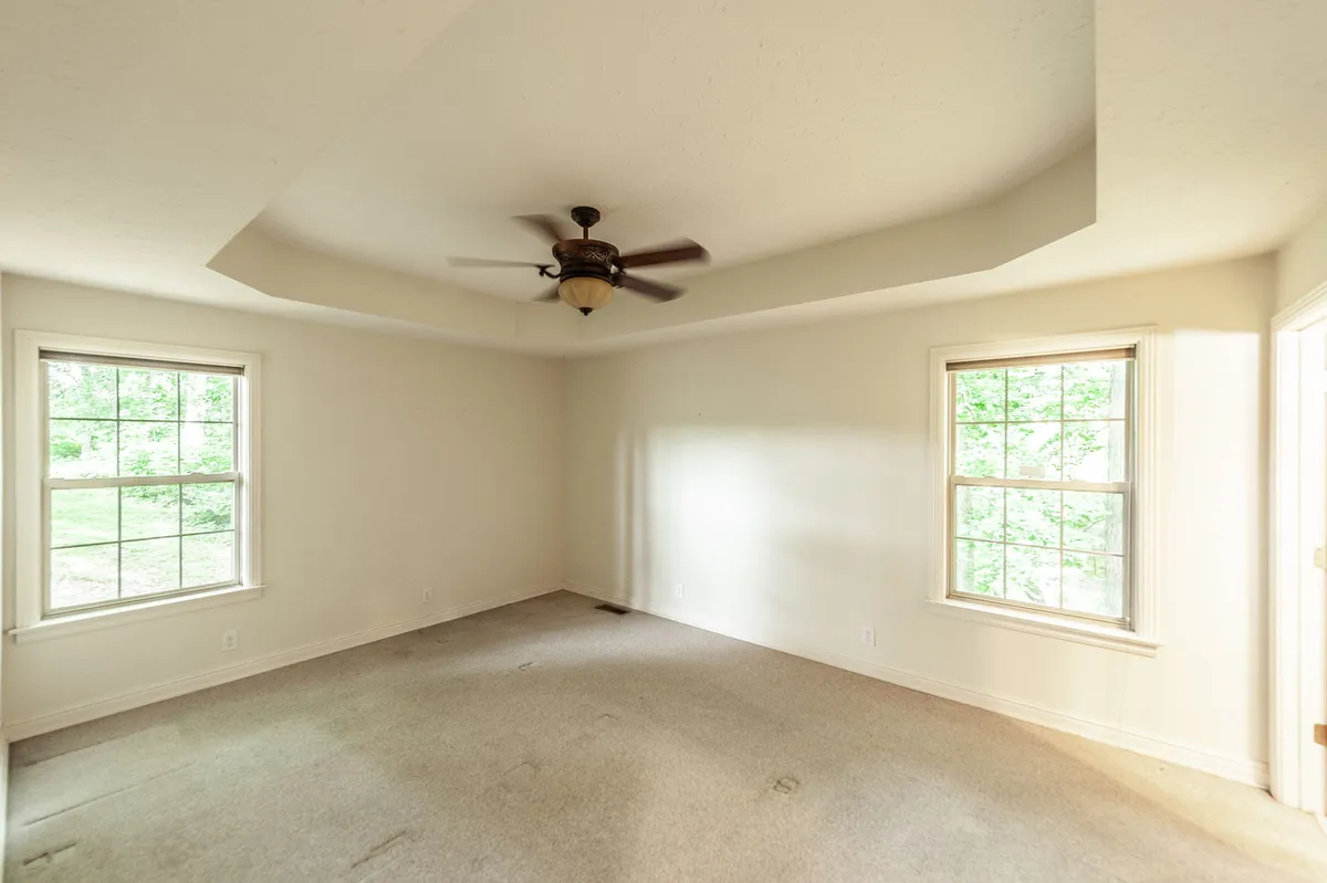 Primary bedroom with a tray ceiling and ceiling fan at 6513 N Mount Pleasant Rd